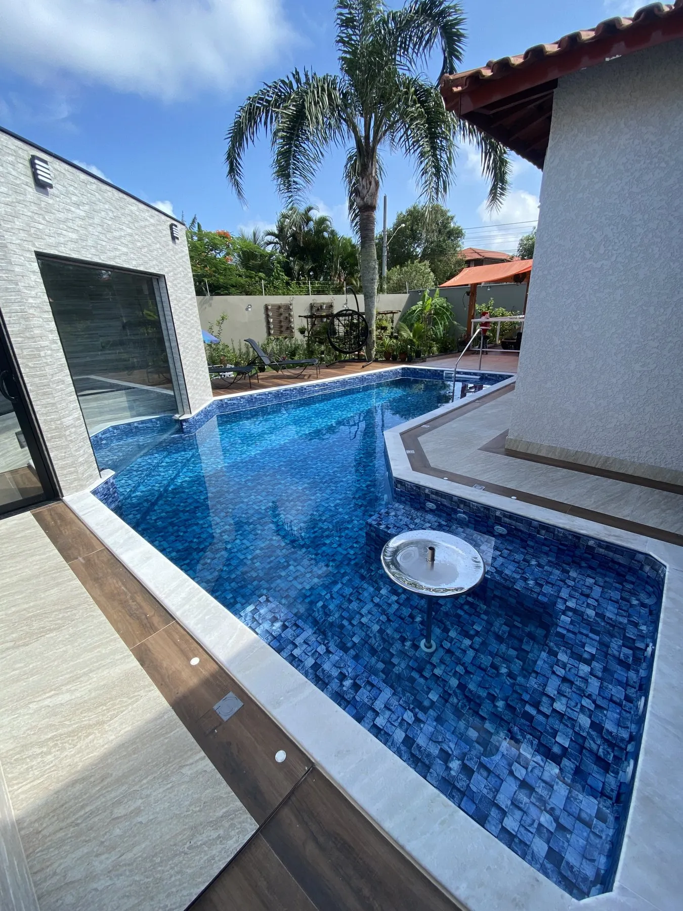 Piscina pronta com pastilhas azuis e coqueiros ao fundo