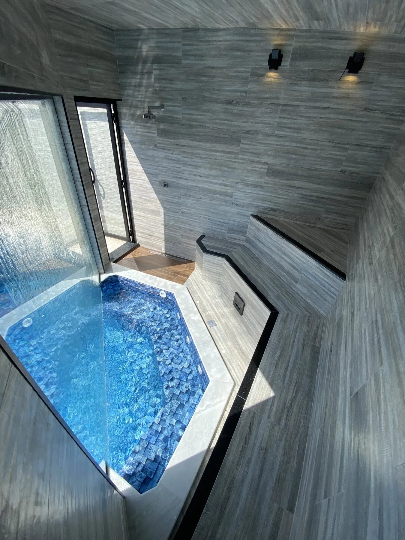 Piscina coberta com pastilhas azuis e revestimento amadeirado